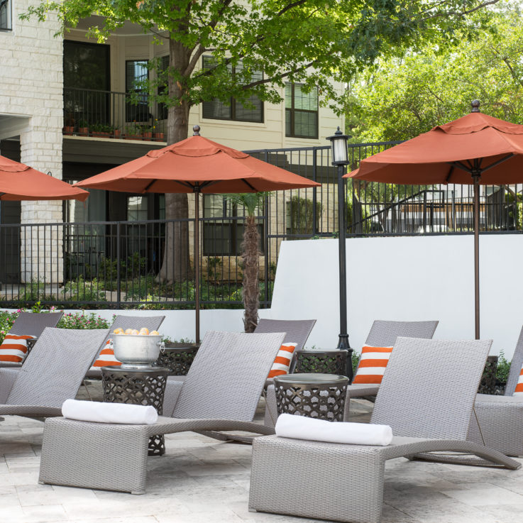 Beach chairs with orange and white striped pillows and orange umbrellas