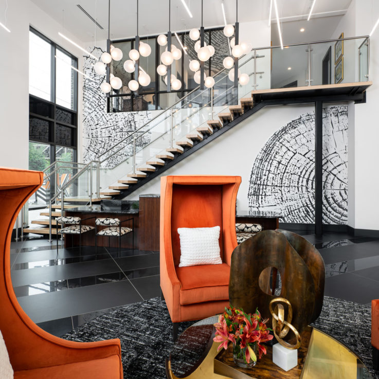 Three orange chairs around a glass coffee table